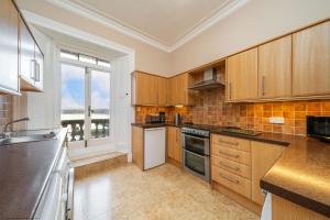 a kitchen with wooden cabinets and a large window at Cleish Apartment in Edinburgh