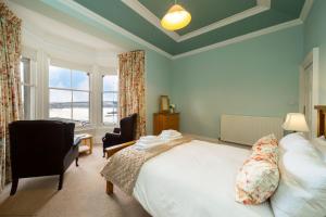 a bedroom with a bed and two chairs and a window at Cleish Apartment in Edinburgh