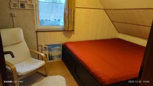una piccola camera da letto con un letto e una sedia di Ruhiges Elbhäuschen nahe Hamburg a Hollern-Twielenfleth