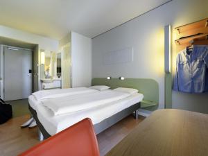 ein Schlafzimmer mit einem großen weißen Bett in einem Zimmer in der Unterkunft ibis budget Muenchen City Olympiapark in München