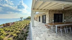 een terras met een tafel en stoelen en de oceaan bij Eosea Helios in Ierissos