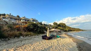 een strand met een parasol en stoelen op het zand bij Eosea Helios in Ierissos