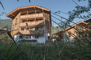 ein Holzgebäude mit einem Balkon auf einem Hügel in der Unterkunft Atelier Garni Astei in Großarl