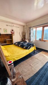 een slaapkamer met een geel bed en een raam bij The Ivy House Sethan in Manāli