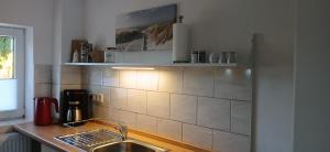 una cucina con lavandino e parete piastrellata di Fewo Seestern a Bremerhaven
