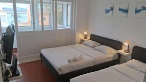 een slaapkamer met twee bedden en twee ramen bij Blife Mariangya private rooms at Faro beach in Faro