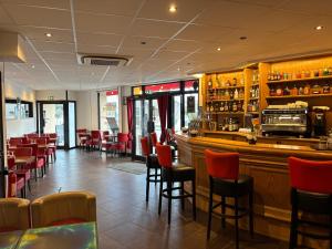 a restaurant with red chairs and a bar at Le Grand Café in Châtillon