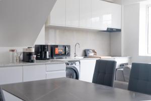 eine Küche mit weißen Schränken und einem Tisch und Stühlen in der Unterkunft Le Van G-Home in Auvers-sur-Oise