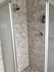 a bathroom with a shower with a glass door at Golden Mile Estate Self Check Inn in eMalahleni