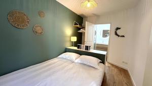 een slaapkamer met een bed met een groene muur bij Le Cours des Arts in Nantes