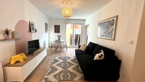 een woonkamer met een zwarte bank en een tv bij Le Cours des Arts in Nantes