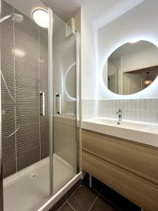 een badkamer met douche, wastafel en spiegel bij Le Cours des Arts in Nantes