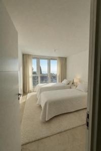 two beds in a white bedroom with a window at Pop villa in La Celle-sous-Gouzon