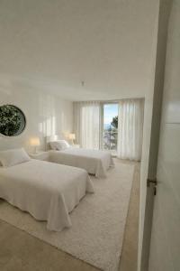 a white bedroom with two beds and a window at Pop villa in La Celle-sous-Gouzon
