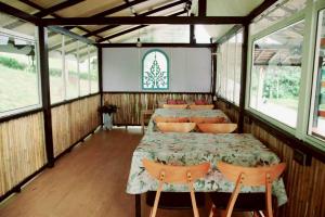 een eetkamer met een tafel, stoelen en ramen bij Grandpa's House in Ko Klang