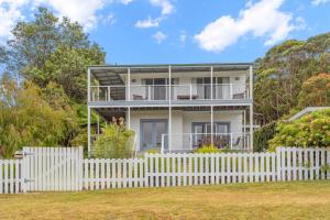 a white picket fence in front of a white house at Bowen View - pet-friendly home near Hyams Beach in Hyams Beach