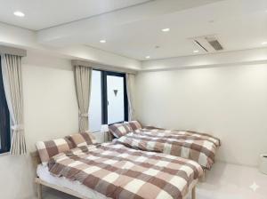 twee bedden in een kamer met ramen bij Hotel LEAP in Osaka