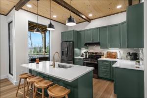 a kitchen with green cabinets and a kitchen island with stools at *Rooftop Deck*Hot Tub*Sauna*Fire Pit*Sunset Views* in Campton