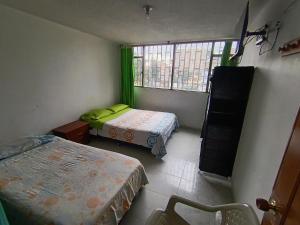 a small room with two beds and a window at Hotel mi casita in Bogotá