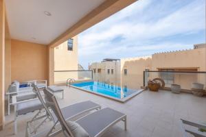 un balcon avec des chaises et une piscine dans un immeuble dans l'établissement Bloomfields al-Fujairah 4BR Villa, Beach Access, à Rūl Ḑadnā