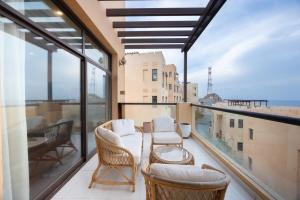 een balkon met stoelen en een tafel en een aantal ramen bij Bloomfields al-Fujairah 4BR Villa, Beach Access in Rūl Ḑadnā