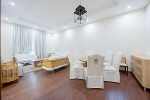 un salon avec des chaises blanches et une table dans l'établissement Bloomfields al-Fujairah 4BR Villa, Beach Access, à Rūl Ḑadnā