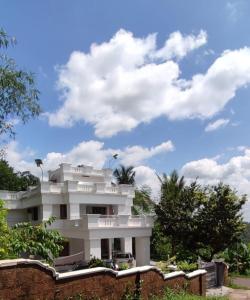 a white house with a blue sky and clouds at A CLASS King bedroom with balcony view, extra bed, and a spacious bathroom with changing area in Chakkarakkal