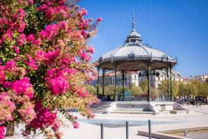 a gazebo with pink flowers in front of a building at L'adorable in Valence