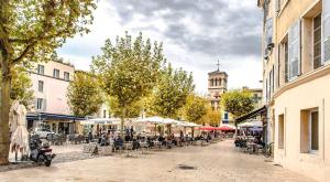 a city street with tables and chairs and a clock tower at L'adorable in Valence +2 photos