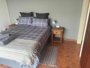 a bedroom with a bed with a gray blanket and a table at Golden Mile Estate Self Check Inn in eMalahleni