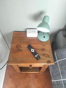 a table with two remote controls and a lamp on it at Golden Mile Estate Self Check Inn in eMalahleni