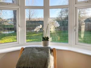 een venster met een tafel en een vaas met witte bloemen bij Island House - Uk51001 in Little Baddow