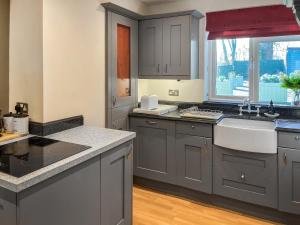 een keuken met grijze kasten, een wastafel en een raam bij Island House - Uk51001 in Little Baddow +13 foto's