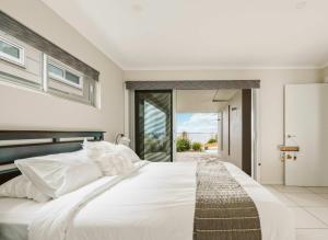 a bedroom with a large white bed with white pillows at Allure at Hyams Beach - seconds to white sands in Hyams Beach