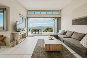 a living room with a couch and a table at Allure at Hyams Beach - seconds to white sands in Hyams Beach +26 photos