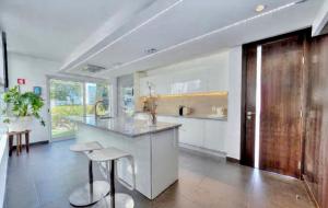 eine Küche mit weißen Schränken, einer Theke und Stühlen in der Unterkunft CASA BRANCA ALGARVE infinity pool & shaded deck in Estói