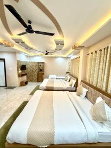 two beds in a large room with a ceiling fan at Hotel The Pushpraj in Varanasi +45 photos