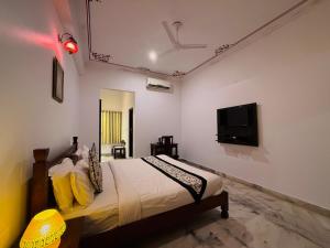een slaapkamer met een bed en een flatscreen-tv bij Atulya Niwas in Udaipur
