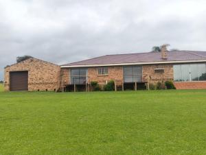 a brick house with a grass field in front of it at Golden Mile Estate Self Check Inn in eMalahleni