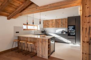 eine Küche mit Holzschränken und eine Insel mit Barhockern in der Unterkunft Chalet Boheme Les Gets - by EMERALD STAY in Les Gets + 36 Fotos