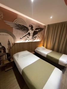 two beds in a room with an angel on the wall at Hôtel Icare in Toulouse