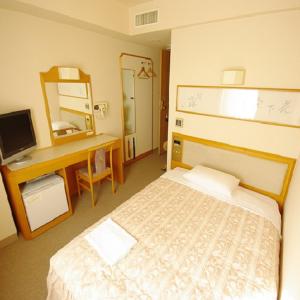 a bedroom with a bed and a desk and a mirror at Hotel Crown Hills Niigata in Niigata