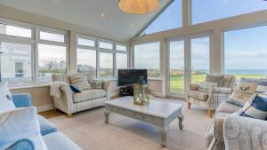 een woonkamer met banken, een tv en ramen bij Hafan Nefyn in Nefyn