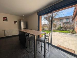 une cuisine avec une table et des chaises ainsi qu'une grande fenêtre dans l'établissement Gite de la grand'cour, à Frampas