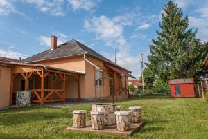 a house with a group of logs in the yard at Annabella Apartman in Tiszafüred