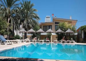 a swimming pool with chairs and umbrellas in front of a building at Paras Sun Hotel & Apartments in Ialysos