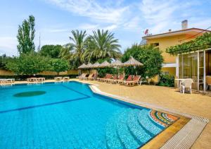 a pool with chairs and umbrellas next to a house at Paras Sun Hotel & Apartments in Ialysos +12 photos