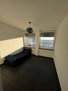 een kamer met een zwarte vloer en twee ramen bij Hotelikum in Heilbronn