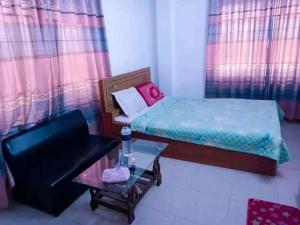 a bedroom with a bed and a chair and a table at রোজ ভ্যালি আবাসিক হোটেল in Dāsnaogaon