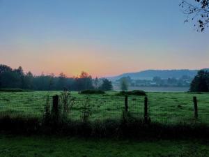 a fence in a field with a sunset in the background at Cottage de Vardes in Neufmarché